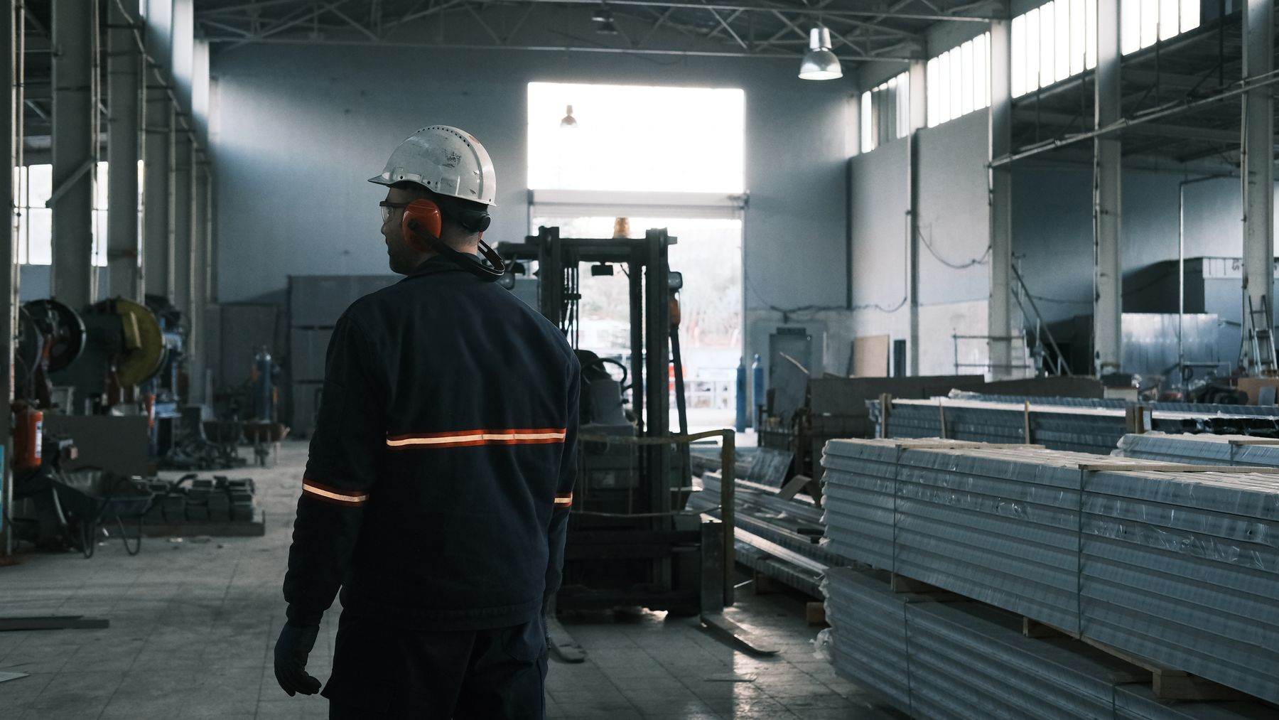 Industriehalle mit Stahlprofilen und einem Mitarbeiter in Schutzkleidung